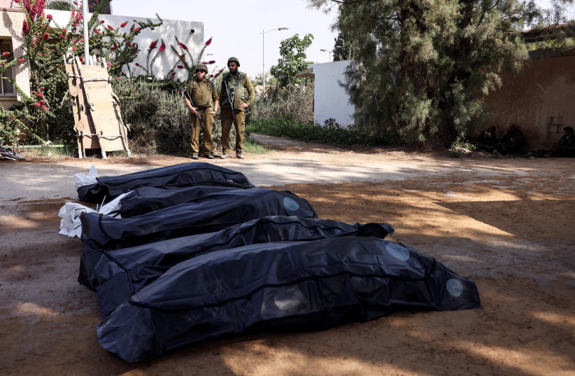  Israeli soldiers guard the bodies of victims of an attack following a mass infiltration by Hamas gunmen from the Gaza Strip, in Kibbutz Kfar Aza, in southern Israel, October 10, 2023. (photo credit: RONEN ZVULUN/REUTERS)