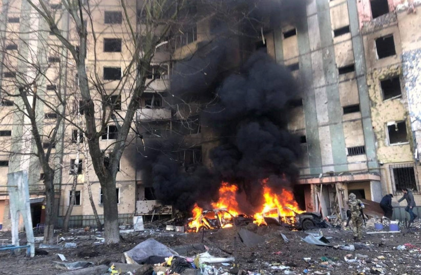 Smoke rises from burning vehicles outside a residential building that has been damaged by an airstrike, as Russia's attack on Ukraine continues, in Kyiv, Ukraine, in this handout picture released March 20, 2022. (photo credit: Press service of the State Emergency Service of Ukraine/Handout via REUTERS)